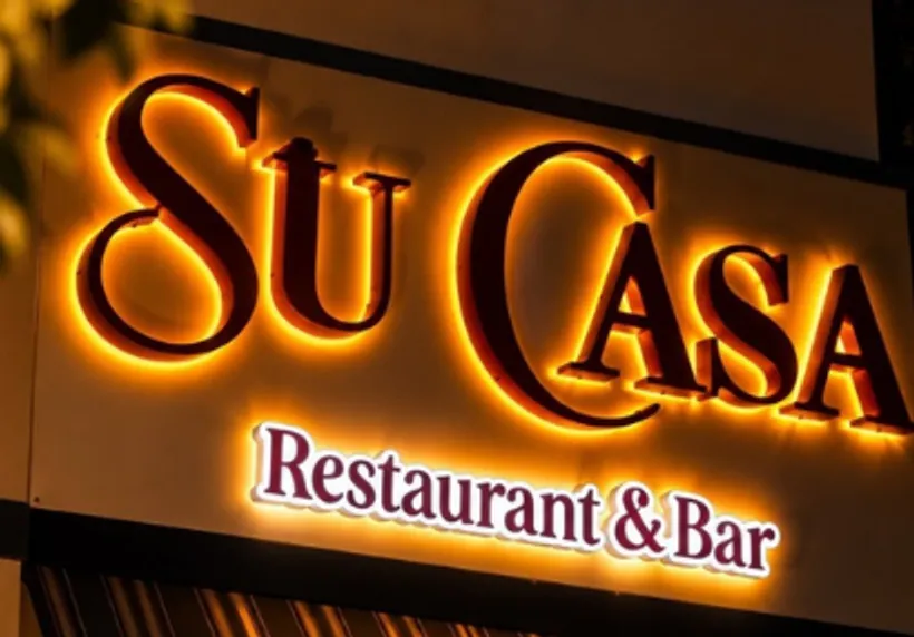 The lit Su Casa Restaurant & Bar sign on the building at dusk