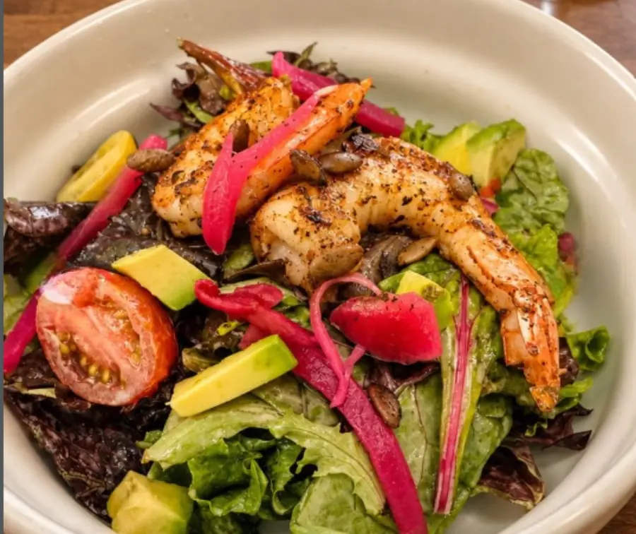 Grilled shrimp over mixed greens with avocado, tomato and pickled onion